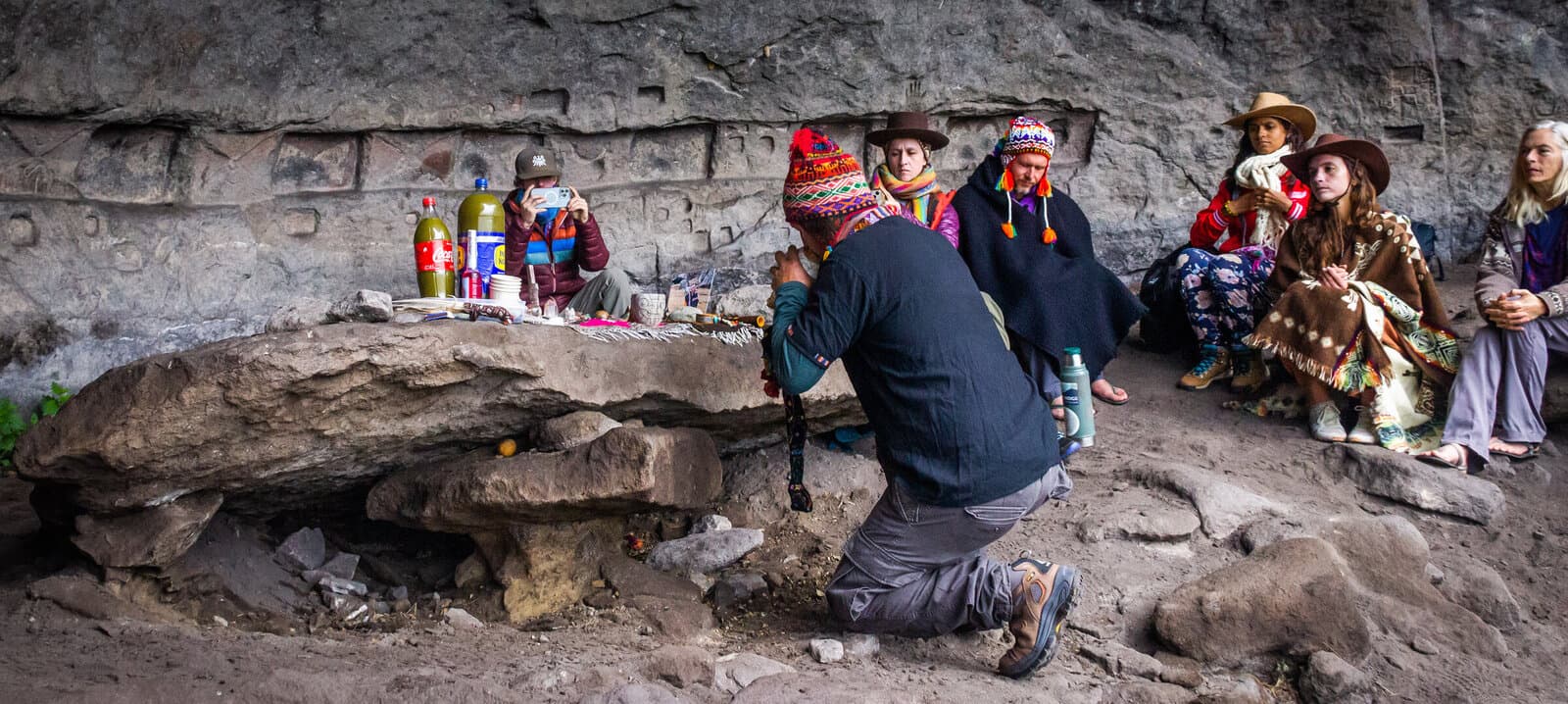 Pilgrim kneeling at a stone-cave mesa during ceremony