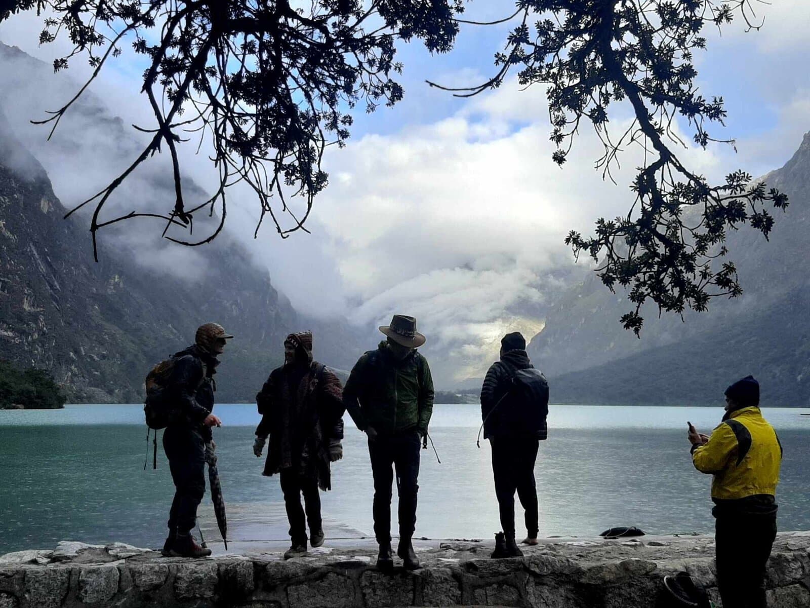 Pilgrims silhouetted at an Andean alpine lake
