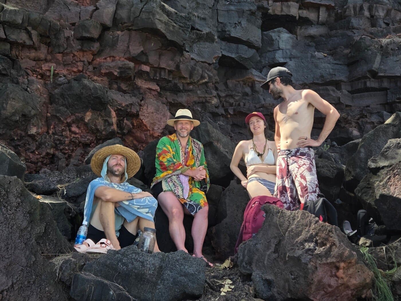 Sacred Ways Hawaii guests gathered on Big Island lava rocks against a dramatic basalt cliff